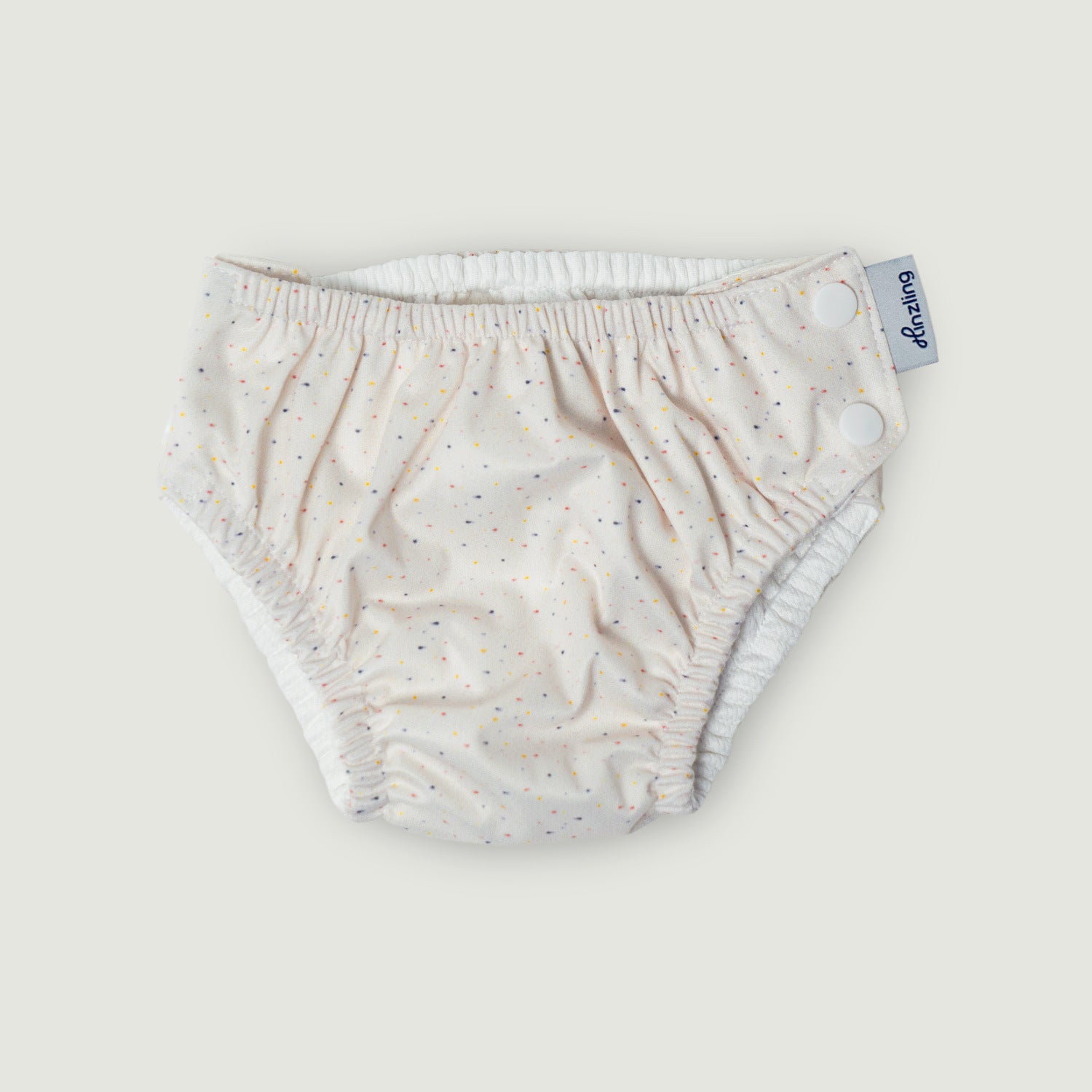 Schwimmwindel mit weißer Farbe und kleinen, bunten Farbpunkten als Muster auf weißem Hintergrund